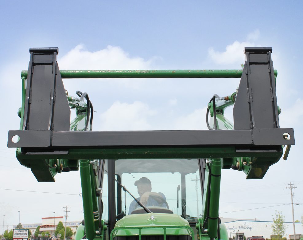 adapter plate attached to loader while farmer smiles happily